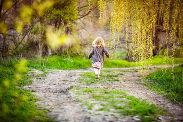 little girl running away from parents in Park.