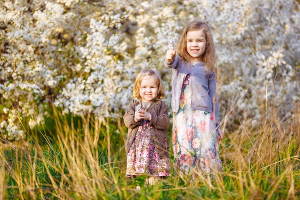 Deux petites filles dans des buissons fleuris avec des brindilles — Photo