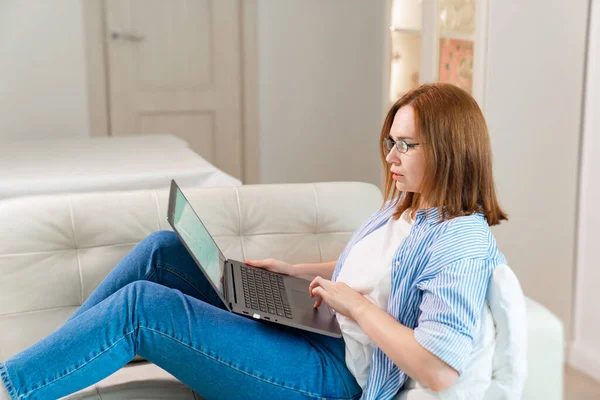 Frilansande kvinna arbetar liggande på soffan med dator — Stockfoto