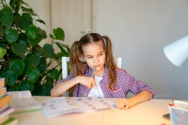 Ekose gömlekli liseli kız evde ders çalışıyor. 