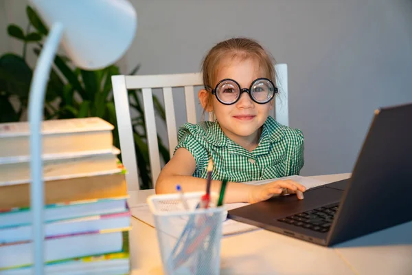 Niña pequeña en gafas grandes aprendizaje en el ordenador portátil . — Foto de Stock