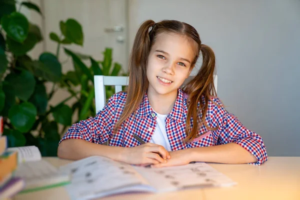 Teenie-Schulmädchen im karierten Hemd bei den Hausaufgaben — Stockfoto