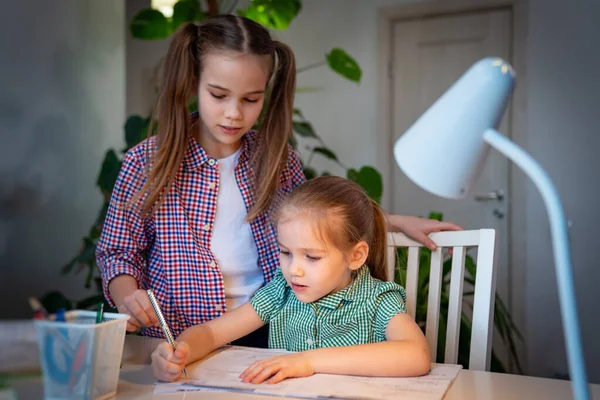 Hermana mayor ayuda a los más jóvenes con sus escritos — Foto de Stock