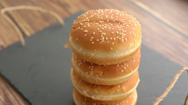 Broodjes met sesam voor hamburgers. zwarte stenen dienblad. — Stockvideo
