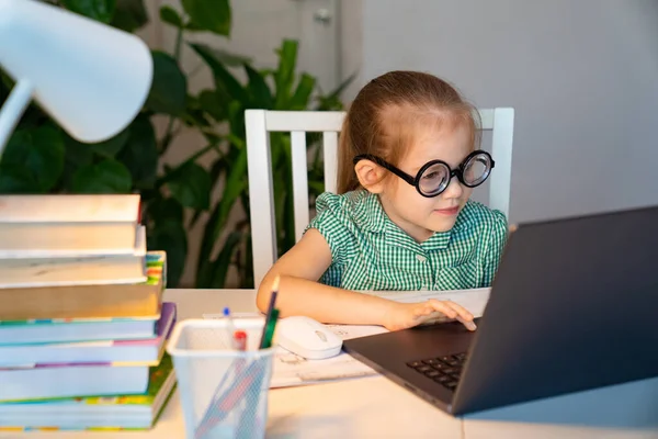 Niña en gafas grandes aprendizaje en el ordenador portátil en línea . — Foto de Stock