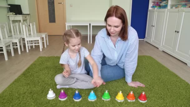 Mamma och flicka leker med färgglada musikaliska klockor. — Stockvideo