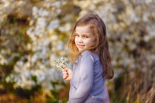 Дівчина в квітучих кущах з гілочкою в руках . — стокове фото