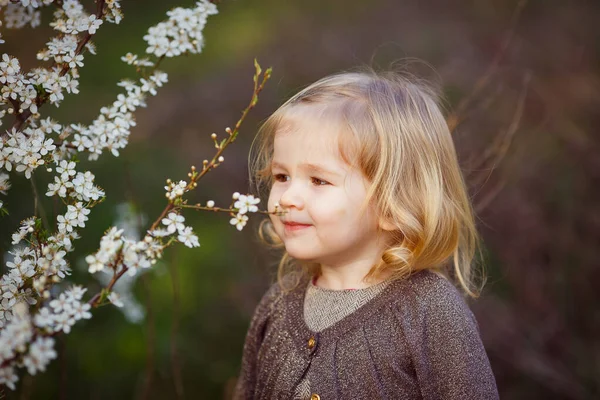 Petite fille blonde dans les fourrés de buissons en fleurs . — Photo