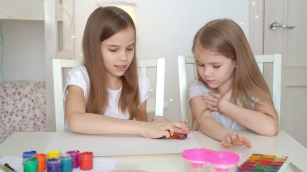 Schwestern zeichnen mit einem Schwamm auf einem weißen Blatt Regenbogen. — Stockvideo