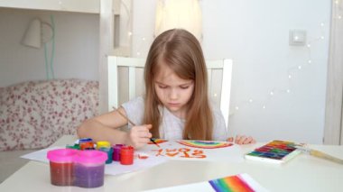 little girl with blond hair drew a rainbow and a poster stay home.