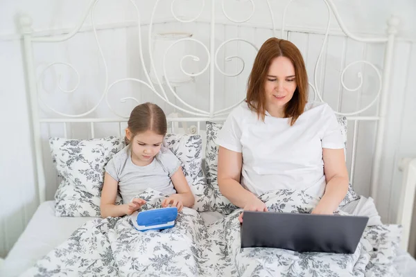 Quedarse en casa chica y mamá jugar en el ordenador en el dormitorio — Foto de Stock