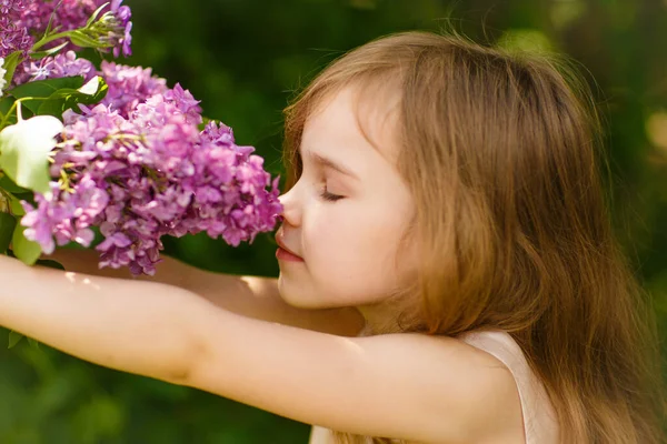 Niña pequeña cerca de flores lila snuff bouquet — Foto de Stock