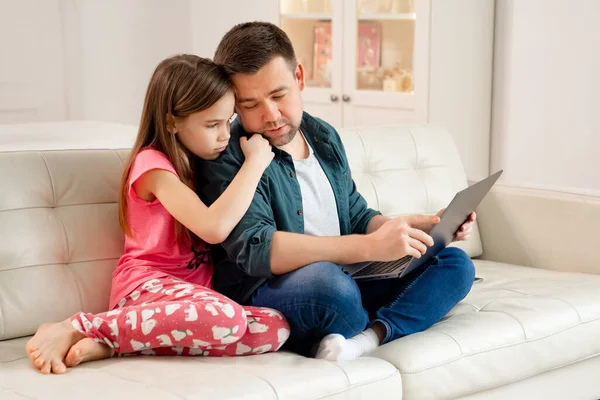 Blogger a dcera pracují na notebooku na gauči. — Stock fotografie