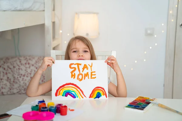 little girl drew rainbow and poster stay home.