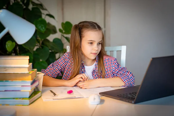 Adolescente chica escucha lección y escribe en un ordenador portátil — Foto de Stock