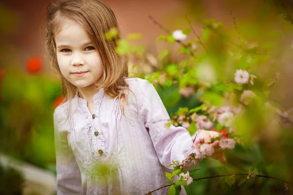 Kleines Mädchen im Garten mit rosa Mandelstrauch — Stockfoto