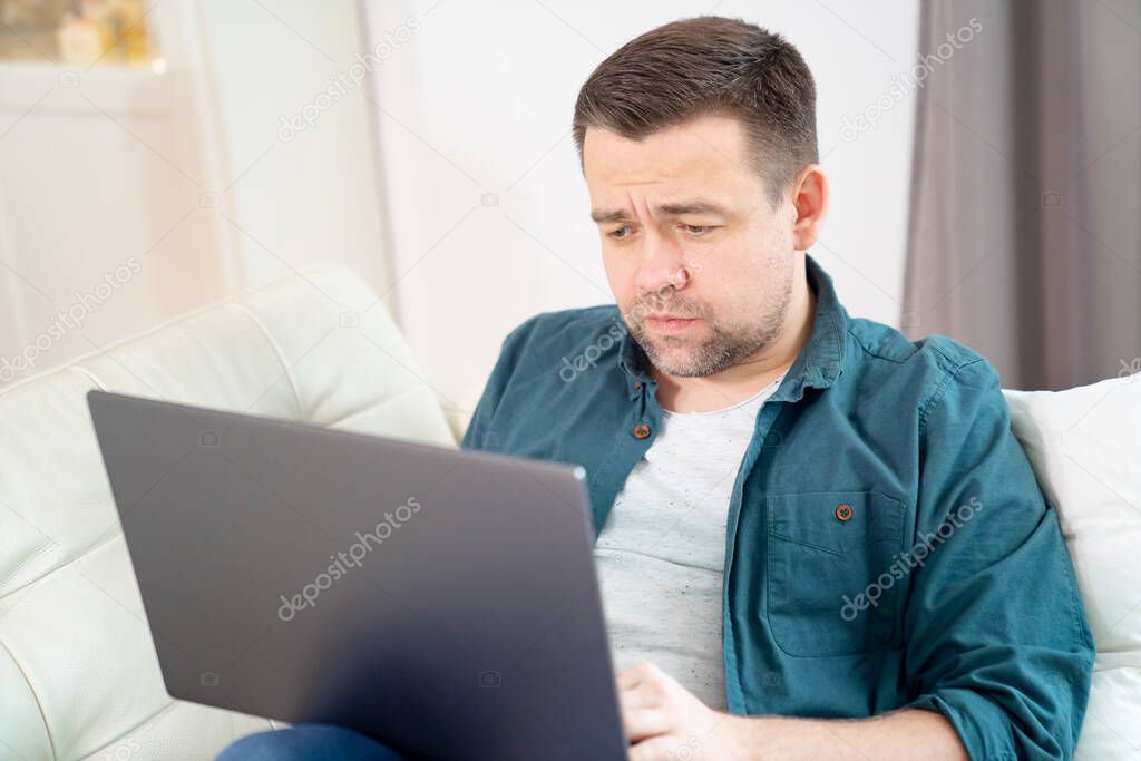 sad male freelancer working online lying on couch.