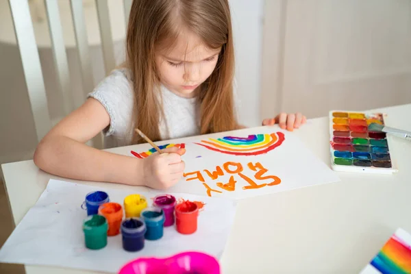 Niña dibujó arco iris y cartel quedarse en casa . — Foto de Stock