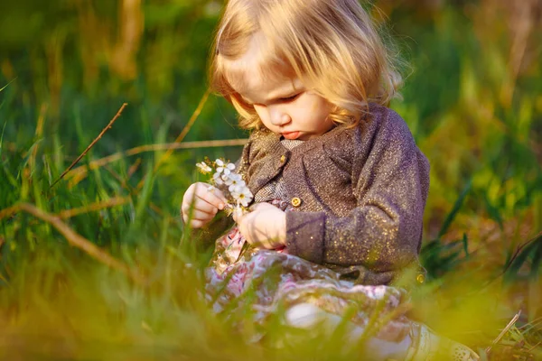 Mädchen sitzt mit blühendem Zweig im Gras — Stockfoto