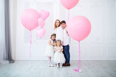 Pembe balonları olan iki kızı olan bir aile..