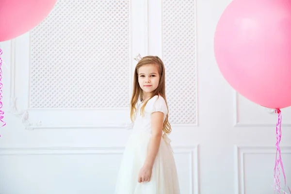 Маленька дівчинка в білій сукні з великими рожевими кульками — стокове фото