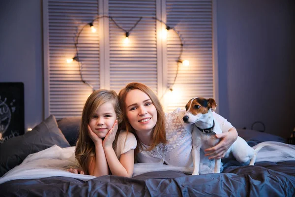 Madre e hija con perro acostado en la cama . — Foto de Stock