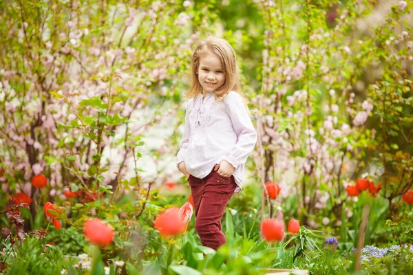 Dulce chica en macizo de flores con almendras y tulipanes — Foto de Stock