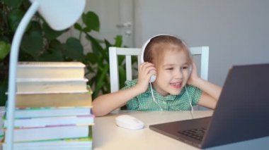 Kulaklıklı küçük kız dizüstü bilgisayardan müzik dinliyor.