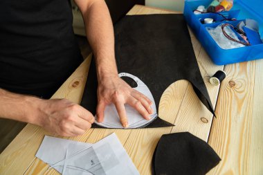 Erkek elleri makasla desen maskesini keser.