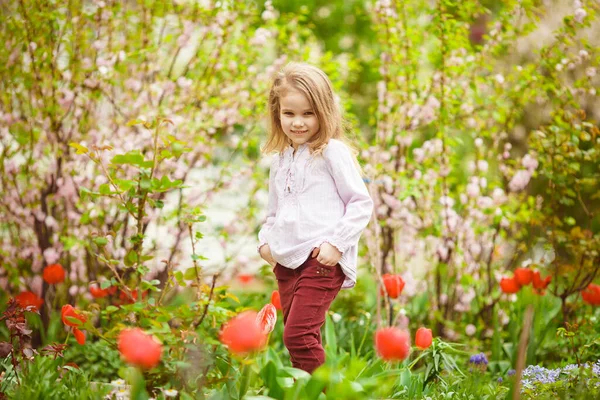Дівчина в клумбі з мигдалем і тюльпанами — стокове фото