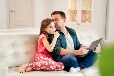 Baba ve kızı kanepede defter üzerinde çalışıyorlar..