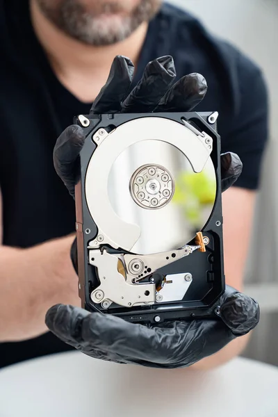 Abrir o disco rígido do computador em mãos em luvas pretas . — Fotografia de Stock