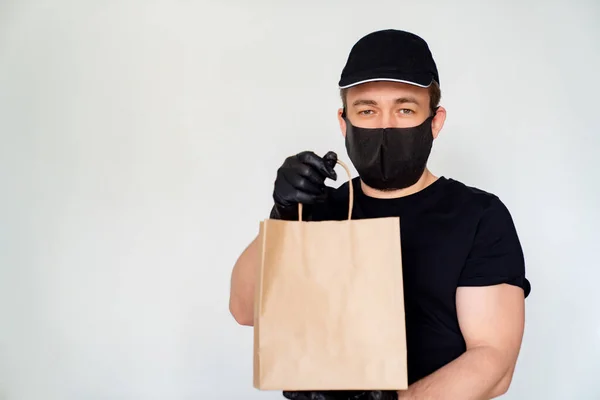 Delivery man in black hold cardboard bag