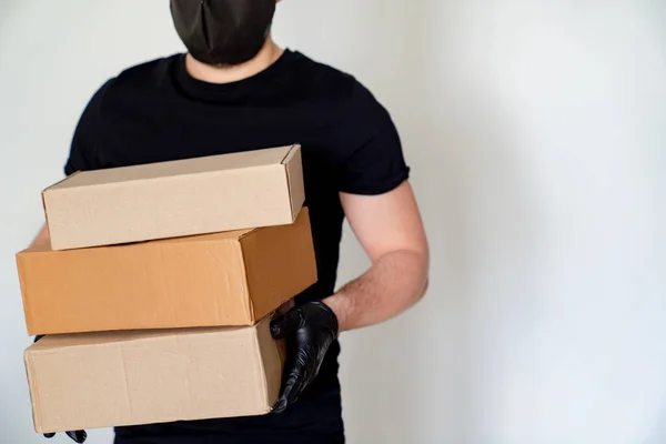 Delivery man in black hold cardboard boxes