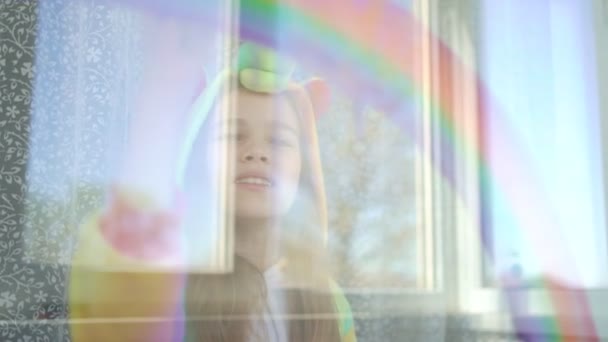 Mädchen im Pyjama zeichnet Regenbogen aufs Fenster. — Stockvideo