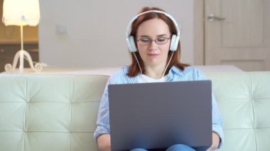 Kadın bilgisayar başında kulaklıkla çalışıyor.