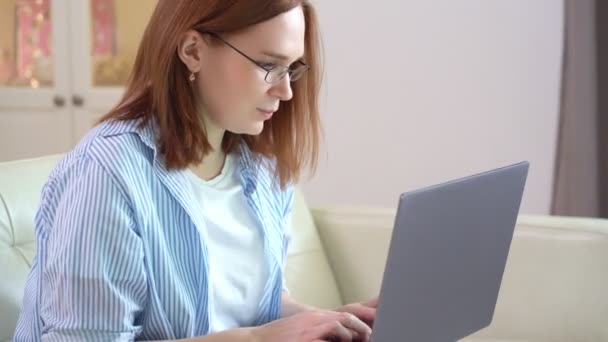 Donna con computer portatile, testo a macchina, seduta sul divano . — Video Stock