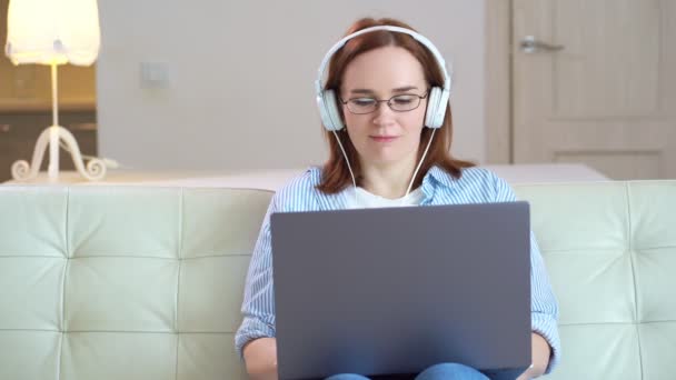 Mujer trabaja en el ordenador con auriculares — Vídeo de stock