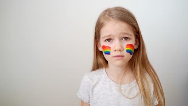 Kleines Mädchen malte Wangen mit einem Regenbogen. Zuhause bleiben. — Stockvideo