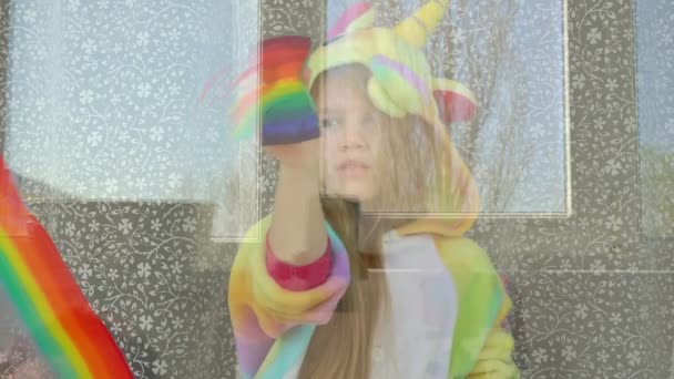 Ребенок в пижаме рисует радугу на окне . — стоковое видео