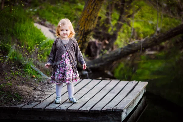 Kleines Mädchen steht auf Holzbrücke am Teich — Stockfoto
