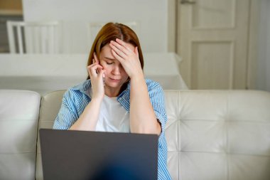 Kanepede telefonla konuşan üzgün bir kadın.