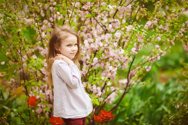 Дівчина в саду з мигдалевим кущем і тюльпанами — стокове фото