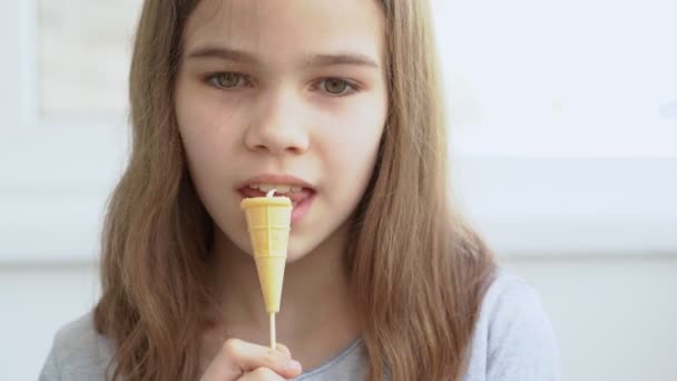 Tenn flicka äter godis i en våffla Cup med grädde. — Stockvideo