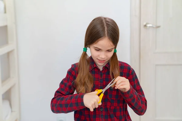 Девушка-подросток стрижет себе волосы ножницами — стоковое фото