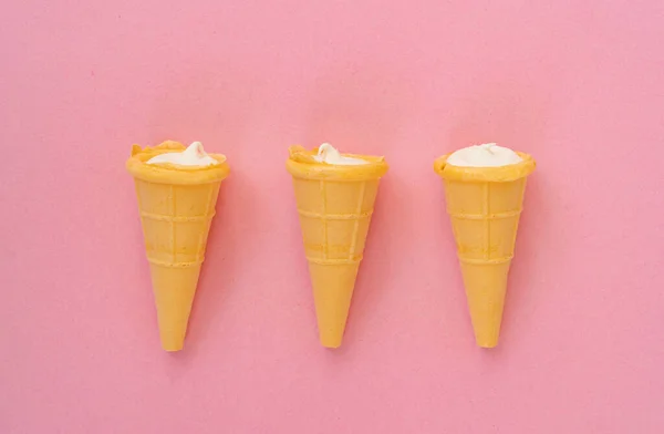 Vanilla cream in wafer cup on pink background.