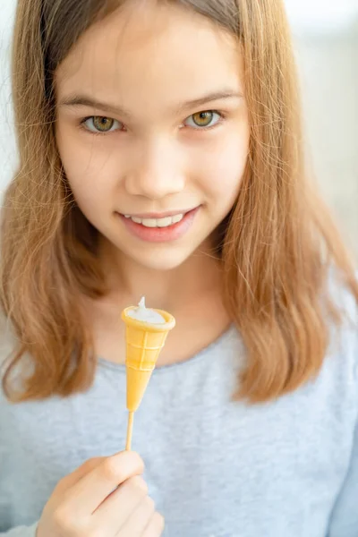 Tenn ragazza mangiare caramelle in una tazza di waffle con crema . — Foto Stock