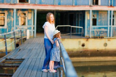 Mavi elbiseli anne ve çocuk eski köprüde duruyor.