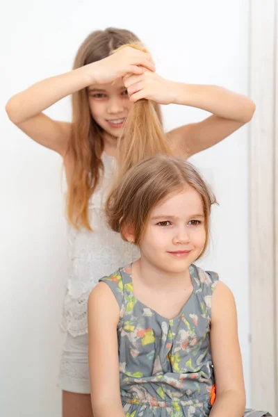 Pequeña niña cepillando el pelo de su hermana menor —  Fotos de Stock