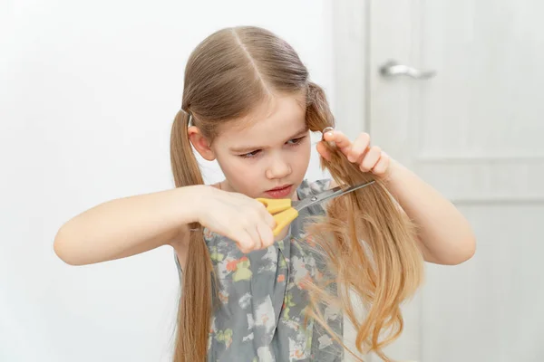 Kleines Mädchen schneidet sich mit Schere die Haare — Stockfoto